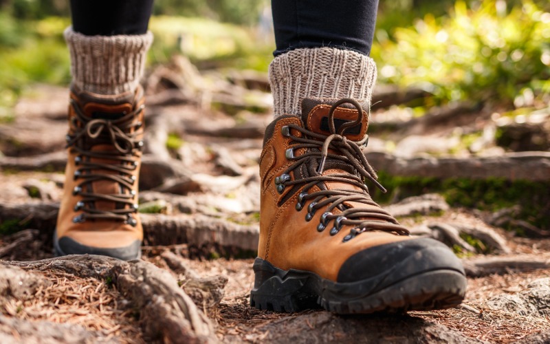 Detail robustnih, visokih pohodniških čevljev in toplih nogavic, ki so ključni za stabilnost in suhost nog v jesenskih razmerah.