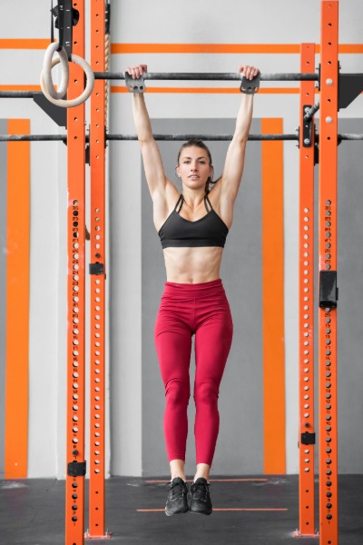 Oseba pravilno izvaja vajo pasivno visenje (dead hang) na drogu za lajšanje bolečine v rami.