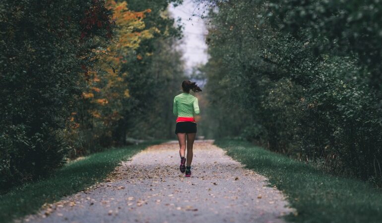 Aktivna oseba teče po jesenskem gozdu, polna energije zaradi močnega imunskega sistema.