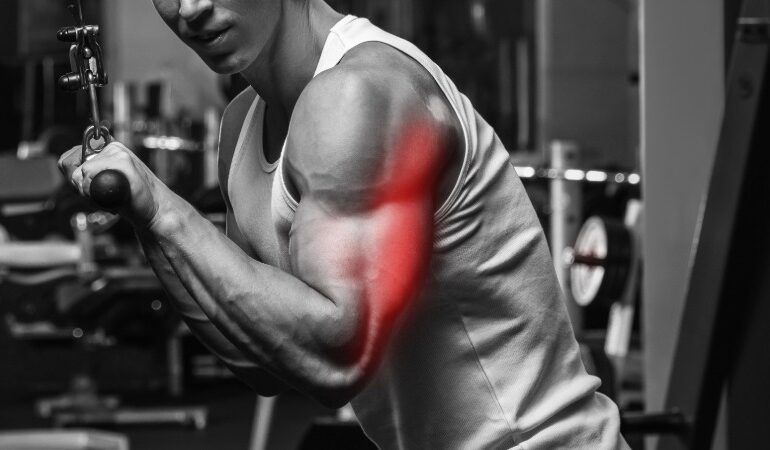 Moški trenira triceps v fitnesu, pri čemer je mišica poudarjena z rdečo barvo, kar ponazarja zavestno povezavo med možgani in mišico.