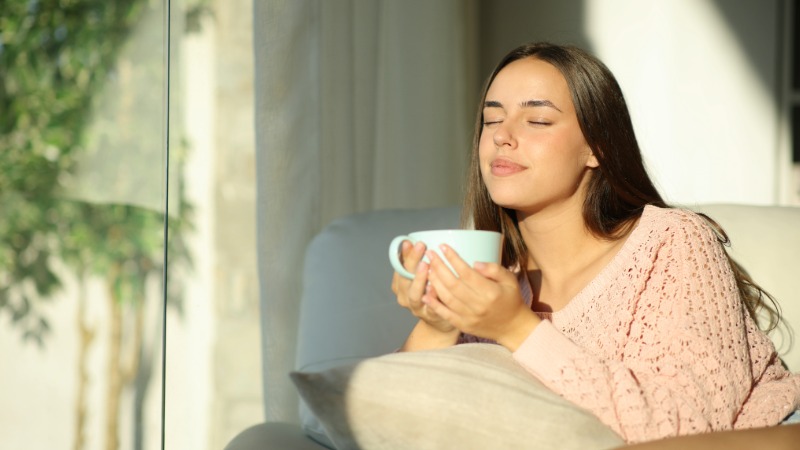 Oseba se sprošča in hidrira s toplim čajem po športni aktivnosti, kar je ključno za uspešno regeneracijo.