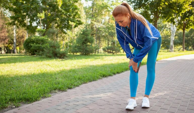 Tekač se med tekom drži za zunanjo stran kolena zaradi bolečine, značilne za ITB sindrom.