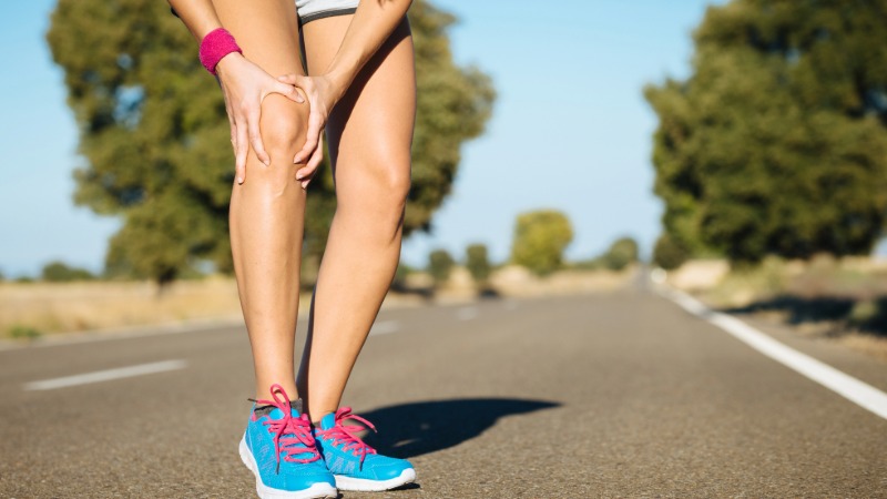 Tekačica ponazarja bolečino v kolenu, ki je pogosta posledica prenizke tekaške kadence.