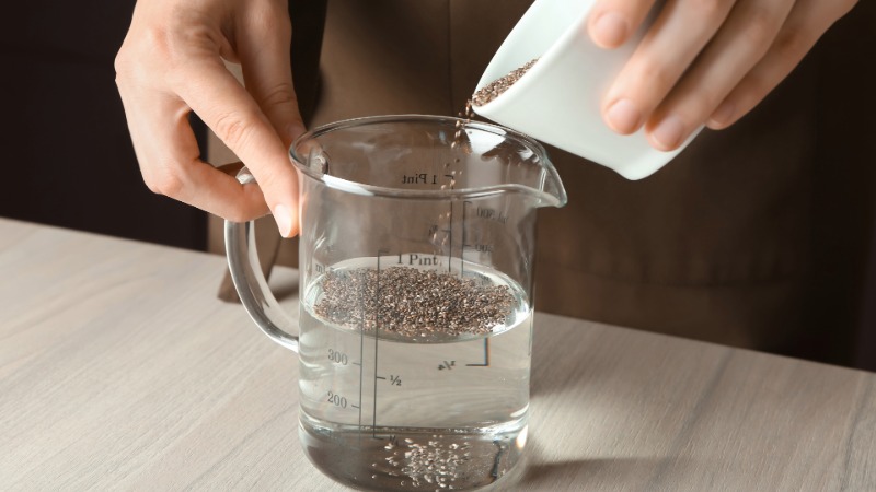 oseba sipa chia semena v vrč z vodo za pripravo chia gela