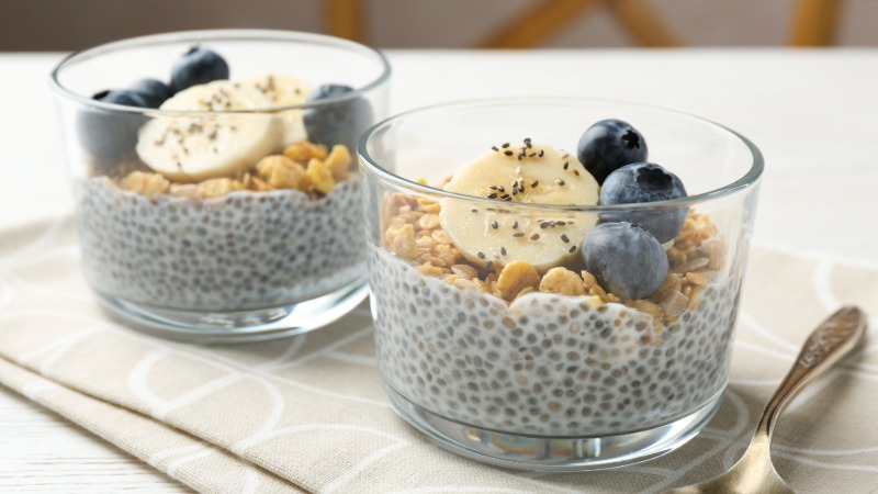 dva kozarca chia pudinga z banano borovnicami in kosmiči za zajtrk