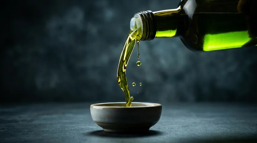 Nalivanje svežega olivnega olja v skodelico