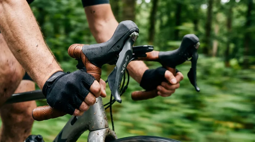 Roke kolesarja na krmilu sodobnega gravel kolesa