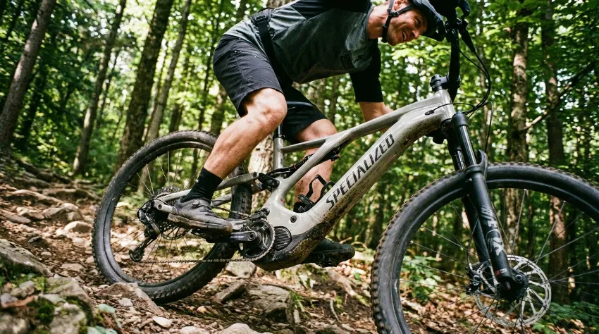 Kolesar na električnem gorskem kolesu med vzponom v gozdu