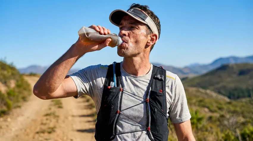 Tekač pije vodo med dolgim tekom za hidracijo