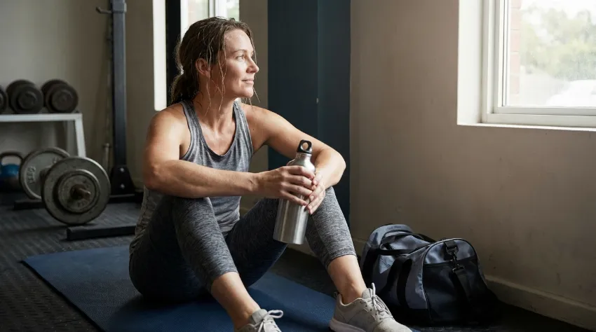 Ženska med pavzo drži plastenko z vodo za ohladitev dlani.