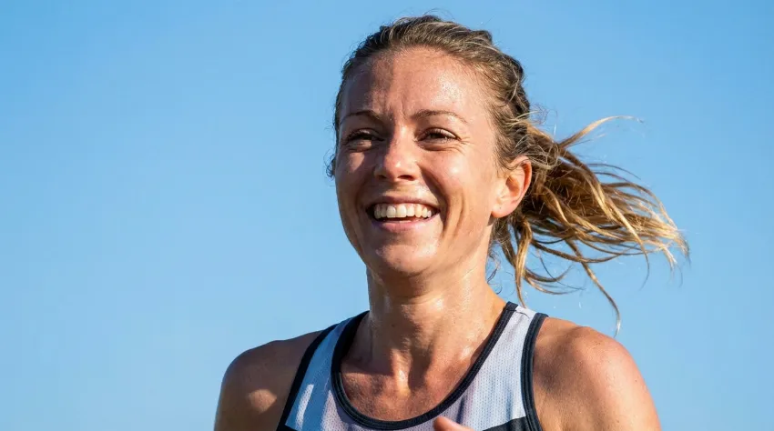 Nasmejana tekačica med tekom v sončnem vremenu