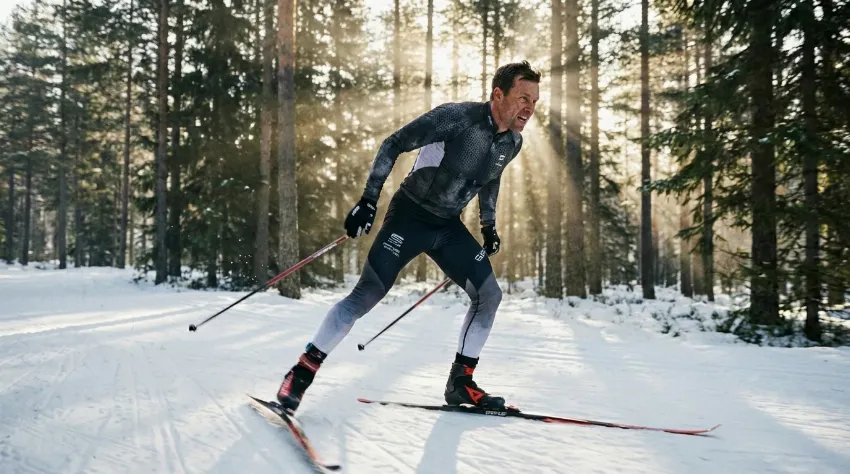 Tekač na smučeh v drsalni tehniki sredi gozda