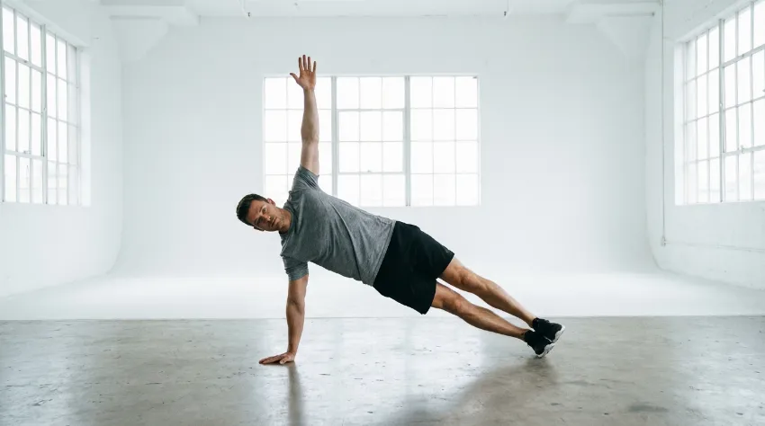 Moški izvaja stranski plank v fitnesu