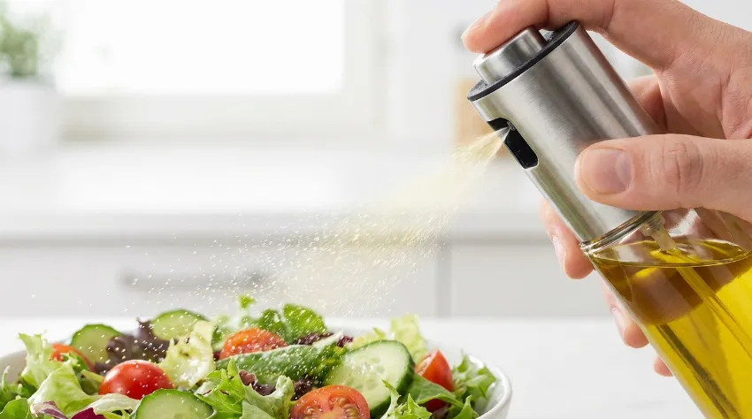 Pršenje oljčnega olja na solato za zmanjšanje vnosa maščob