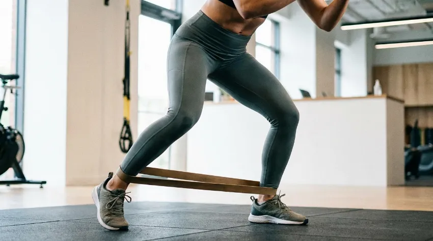 Ženska izvaja vajo monster walk z elastiko okoli gležnjev