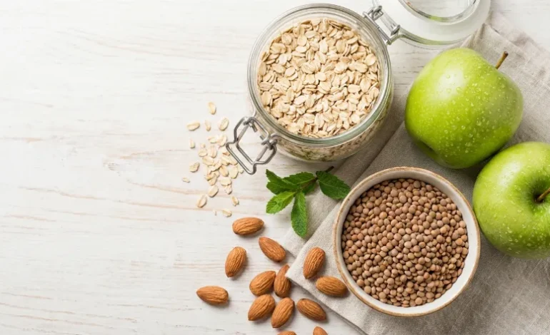 Zbirka naravnih živil za zniževanje holesterola: oves, jabolka, leča in mandlji na mizi