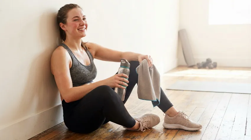 Sproščena ženska po vadbi pilatesa ob steni