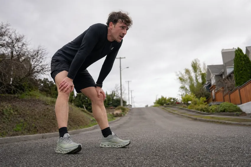 Tekač naslonjen na kolena po prehitrem začetku teka brez ustreznega ogrevanja.