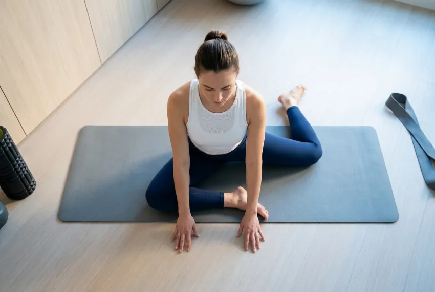 Pogled od zgoraj na žensko, ki na tleh izvaja vajo za kolke v položaju 90/90.