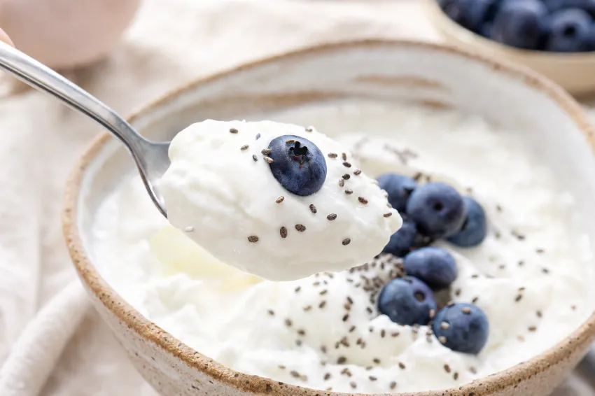 Od blizu posneta žlica, ki zajema gost grški jogurt z borovnicami in chia semeni.