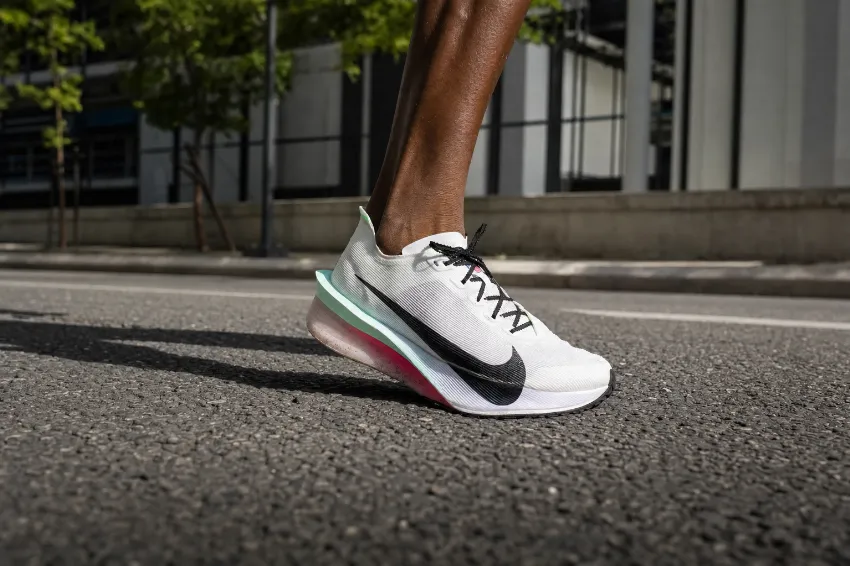 Karbonska tekaška superga Nike Vaporfly ob stiku z asfaltom, slika od blizu.