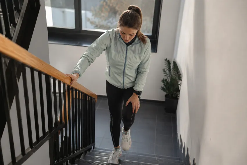 Tekač po maratonu previdno hodi po stopnicah navzdol